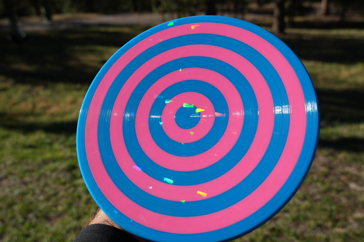 CC-001 Spin Rings prototype with blue and pink concentric rings photographed outdoors